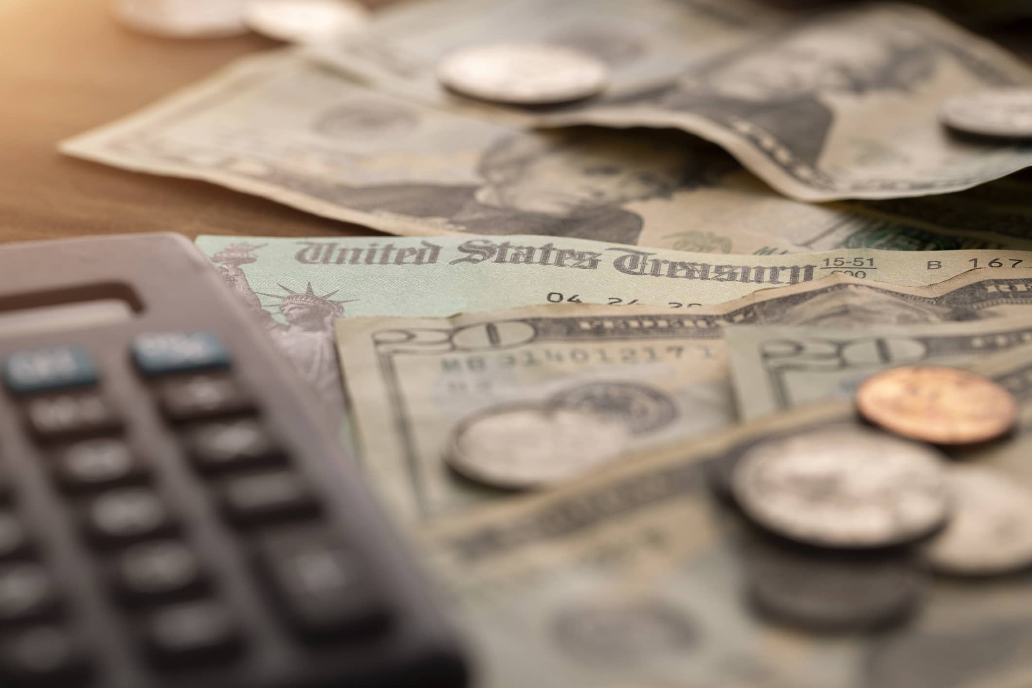 Close-up of paper money, coins, and a calculator